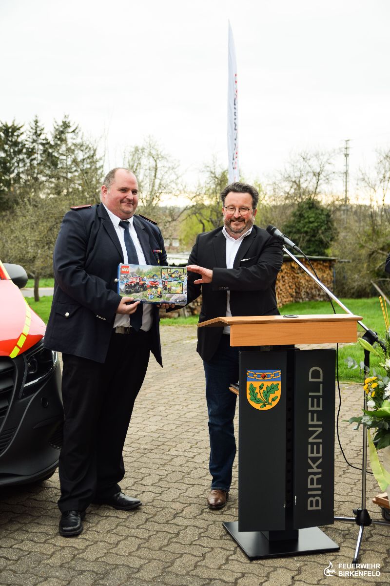 Jens Dann, links im Bild, bekommt von Bürgermeister Steiner (r.) ein Lego-Bausatz überreicht.
