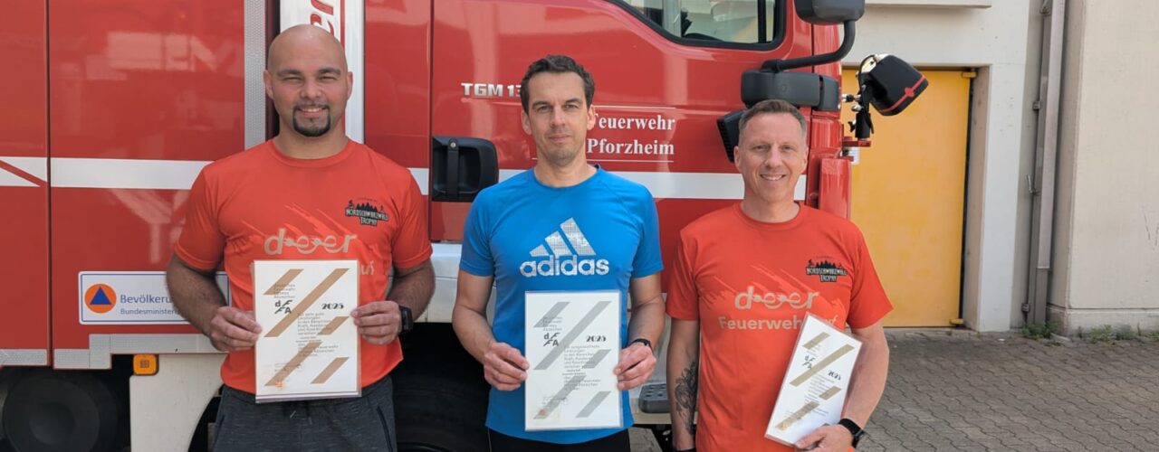 Teilnehmer mit Urkunde vor Feuewehrfahrzeug